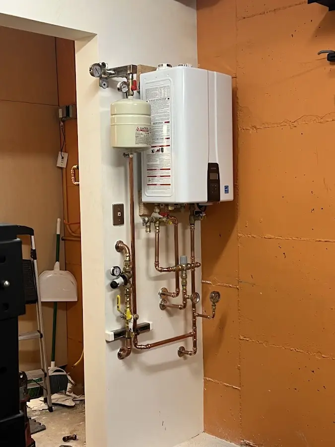 Plumbing technician inspecting water heater connections in Clay